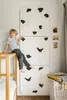 A young boy is sitting on the edge of a bed next to a climbing wall installed in a child's room. Anteprima dell’immagine prodotto