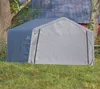 A gray portable shelter or garage is set up on a grassy lawn in front of a barn. Produktbild-Vorschau