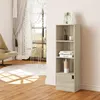 A tall, narrow bookshelf with a single door at the bottom, placed in a room with a chair, a round rug, and a window with curtains. Produktbild-Vorschau