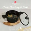 A black pot filled with vegetables and water, with its glass lid open and resting beside it. The pot is placed on a wooden board with a white cloth underneath. The background is a light gray color. Náhled obrázku produktu