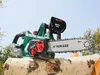 A cordless chainsaw rests on a log, with trees and a blue sky in the background. Produktbild-Vorschau