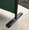 Close-up of the base of a green paravent, showing its metal stand and anchoring plate on a paved surface. Produktbild-Vorschau