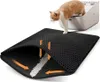 A cat is stepping out of a litter box onto a black litter-trapping mat. The mat is shown with a cutaway to illustrate how litter falls through the honeycomb-like surface into a lower layer, with orange arrows indicating the flow. Náhled obrázku produktu