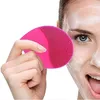 Leuchtend rosa Silikon-Gesichtsreinigungsbürste, in einer Hand gehalten, wird mit Schaum auf dem Gesicht einer Person verwendet Anteprima dell’immagine prodotto