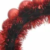 A close-up view of a festive headband decorated with red ornaments and tinsel. Produktbild-Vorschau