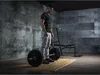 A man is standing in a gym, preparing to lift weights. Náhľad obrázku produktu