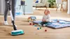 A person is cleaning the floor with a mop while a baby plays nearby. Voir les images du produit