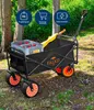 A black foldable electric wagon with orange wheels is shown outdoors in a wooded area, with a crate of bottles inside. Produktbild-Vorschau
