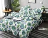 A neatly made bed with a tropical leaf pattern duvet cover and pillows, set in a bedroom with a plant and bedside table. Náhled obrázku produktu
