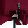 A close-up of a sewing tool attached to a piece of maroon fabric. Náhľad obrázku produktu
