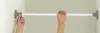 Hands adjusting a telescopic tension rod in a doorway or closet. Produktbild-Vorschau
