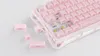 A pink mechanical keyboard with some keycaps removed, lying on a white surface. Produktbild-Vorschau