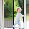 A young child is standing in a doorway with a screen door. Náhled obrázku produktu