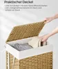 A person's hands are shown placing laundry into a woven basket with a lid. Produktbild-Vorschau