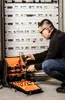An electrician is working on a fuse box with a tool bag next to him. Náhľad obrázku produktu