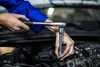 A person's hands are shown working on a car engine with a socket wrench. Produktbild-Vorschau