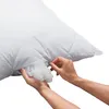Hands are shown adjusting the filling of a white quilted pillow. Produktbild-Vorschau