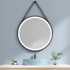 A round LED bathroom mirror with a black leather strap hangs above a light blue sink. Produktbild-Vorschau