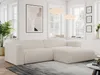 A modern living room with a large, beige corduroy sectional sofa as the focal point. The sofa is placed on a rug in front of a window with natural light streaming in. Artwork and plants add decorative elements to the scene.