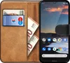A book-style phone case is open, showing cards and cash inside, with a smartphone displaying a landscape image and app icons. Náhled obrázku produktu