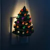A ceramic Christmas tree night light plugged into a wall outlet. Náhľad obrázku produktu