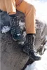 A person wearing winter boots is sitting on a rock with snow around. Produktbild-Vorschau