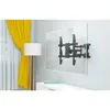 A TV wall mount is attached to a large, clear screen mounted on a wall, with a yellow curtain and a floor lamp in the background. Podgląd zdjęcia produktu