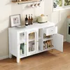 A white sideboard with glass doors and a drawer, filled with various items, is shown in a room setting. Produktbild-Vorschau