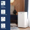 A white portable air conditioner is shown in a room with wooden wall panels, a dark blue cabinet, and a rug. Produktbild-Vorschau