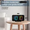 A digital alarm clock is placed on a wooden table, with text overlays providing product information. Produktbild-Vorschau