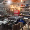 A cluttered workshop with tools, a red toolbox, and a large item covered in plastic wrap. Produktbild-Vorschau