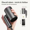 A hand holding a compact gray hairdryer, with a comparison graphic showing its size relative to a smartphone. Produktbild-Vorschau