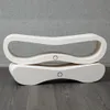 Two white, curved cat scratching posts are stacked on top of each other, set against a textured gray background and a dark wooden floor. Produktbild-Vorschau