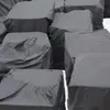A pile of black tarp-covered objects, likely pallets or boxes, stacked outdoors. Produktbild-Vorschau