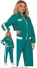A woman is wearing a teal tracksuit with white stripes, posing for a product image. A smaller inset image shows the same tracksuit on a different model. Produktbild-Vorschau