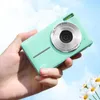 A hand holding a green digital camera against a sky background with daisies in the foreground. Produktbild-Vorschau