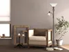 A cozy living room corner with a chair, lamp, and decorative frames. Produktbild-Vorschau