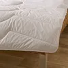 A close-up view of a white comforter or duvet, showing its quilted texture and stitching. Produktbild-Vorschau