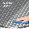 A hand is cleaning a round table with a blue sponge. Voir les images du produit