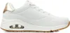 A side view of a white Skechers sneaker with gold accents and a brown sole. Voir les images du produit