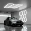 A modern garage with a silver car, illuminated by hexagonal LED lights on the ceiling and wall. Voir les images du produit