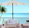 A patio scene with a chair, table, umbrella, and a palm tree by a pool overlooking the ocean. Náhľad obrázku produktu