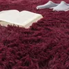 A close-up view of a fluffy, burgundy rug with an open book and a pair of slippers on it. Voir les images du produit