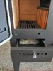 A close-up view of the interior of a wood-burning stove, showing the grate and a pull-out ash drawer. Produktbild-Vorschau