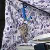 A close-up view inside a bag, showing a set of keys attached to a blue carabiner clip. Anteprima dell’immagine prodotto