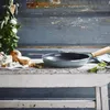 A frying pan and ingredients are arranged on a rustic wooden table against a distressed blue wooden background. Náhled obrázku produktu