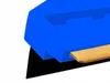 A close-up, angled view of a blue ice scraper with a brass blade. Náhled obrázku produktu