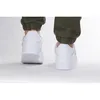 A rear view of a person wearing white Puma sneakers and dark green pants. Produktbild-Vorschau