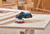 A Bosch cordless orbital sander is placed on a wooden surface next to a wooden frame in a workshop setting. Anteprima dell’immagine prodotto