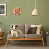 A dog is lying on a sofa in a living room, with a clock on the wall. Produktbild-Vorschau